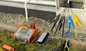 Przyrząd do pomiaru rezystancji izolacji podłączony do przewodów instalacji elektrycznej.