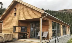 Nowoczesny dom norweski z drewnianą elewacją, tarasem i widokiem na las.