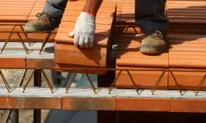 Budowa stropów ceramicznych. Pracownik w rękawicy układa cegły na konstrukcji zbrojeniowej.