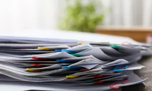 Stos dokumentów, wśród których znajduje się wniosek o zmianę nieprzekraczalnej linii zabudowy. Kolorowe spinacze porządkują papiery.