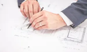 Rysowanie planów budowlanych. Czy można zmienić plan zagospodarowania przestrzennego? Inżynierowie analizują dokumentację techniczną.