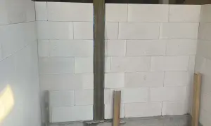 Ściany z bloczków betonowych, widoczne rodzaje dylatacji, pionowy słup drewniany i podpora.