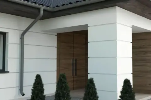 Nowoczesny dom z białym boniowaniem, drewnianymi drzwiami i ozdobnymi elementami elewacji.