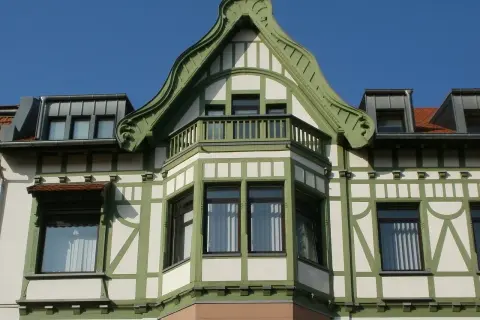 Elegancki ryzalit z zielonymi zdobieniami i balkonem, część fasady secesyjnej kamienicy.