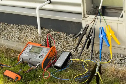 Przyrząd do pomiaru rezystancji izolacji podłączony do przewodów instalacji elektrycznej.
