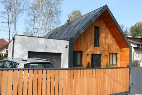 Nowoczesna dobudówka do domu bez pozwolenia, z drewnianą elewacją i garażem.