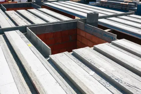 Budowa domu: betonowe belki stropowe czekają na montaż. To właśnie strop co to jest, decyduje o podziale pięter.