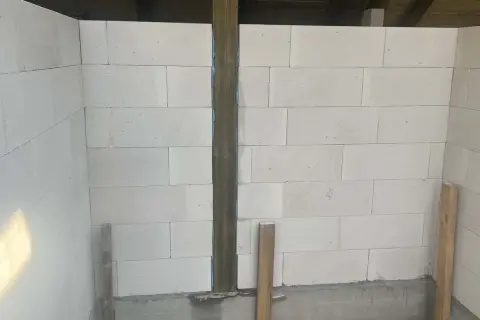 Ściany z bloczków betonowych, widoczne rodzaje dylatacji, pionowy słup drewniany i podpora.