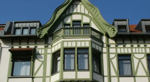 Elegancki ryzalit z zielonymi zdobieniami i balkonem, część fasady secesyjnej kamienicy.