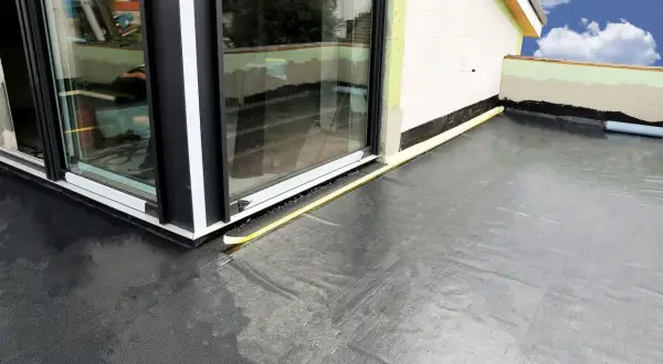Nowy balkon z profesjonalną hydroizolacją. Czarna membrana zabezpiecza przed wilgocią, a żółta taśma uszczelnia połączenie ze stolarką okienną.