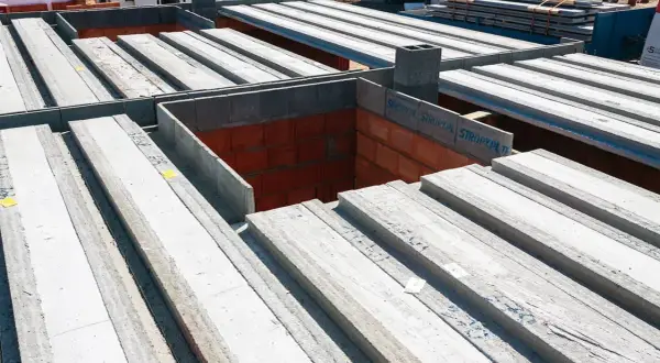 Budowa domu: betonowe belki stropowe czekają na montaż. To właśnie strop co to jest, decyduje o podziale pięter.