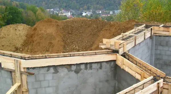 Fundamenty domu w budowie, zbrojenie i szalunki gotowe do zalania betonem. To pierwszy krok do pozwolenia na budowę.
