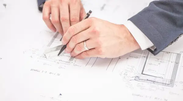 Rysowanie planów budowlanych. Czy można zmienić plan zagospodarowania przestrzennego? Inżynierowie analizują dokumentację techniczną.