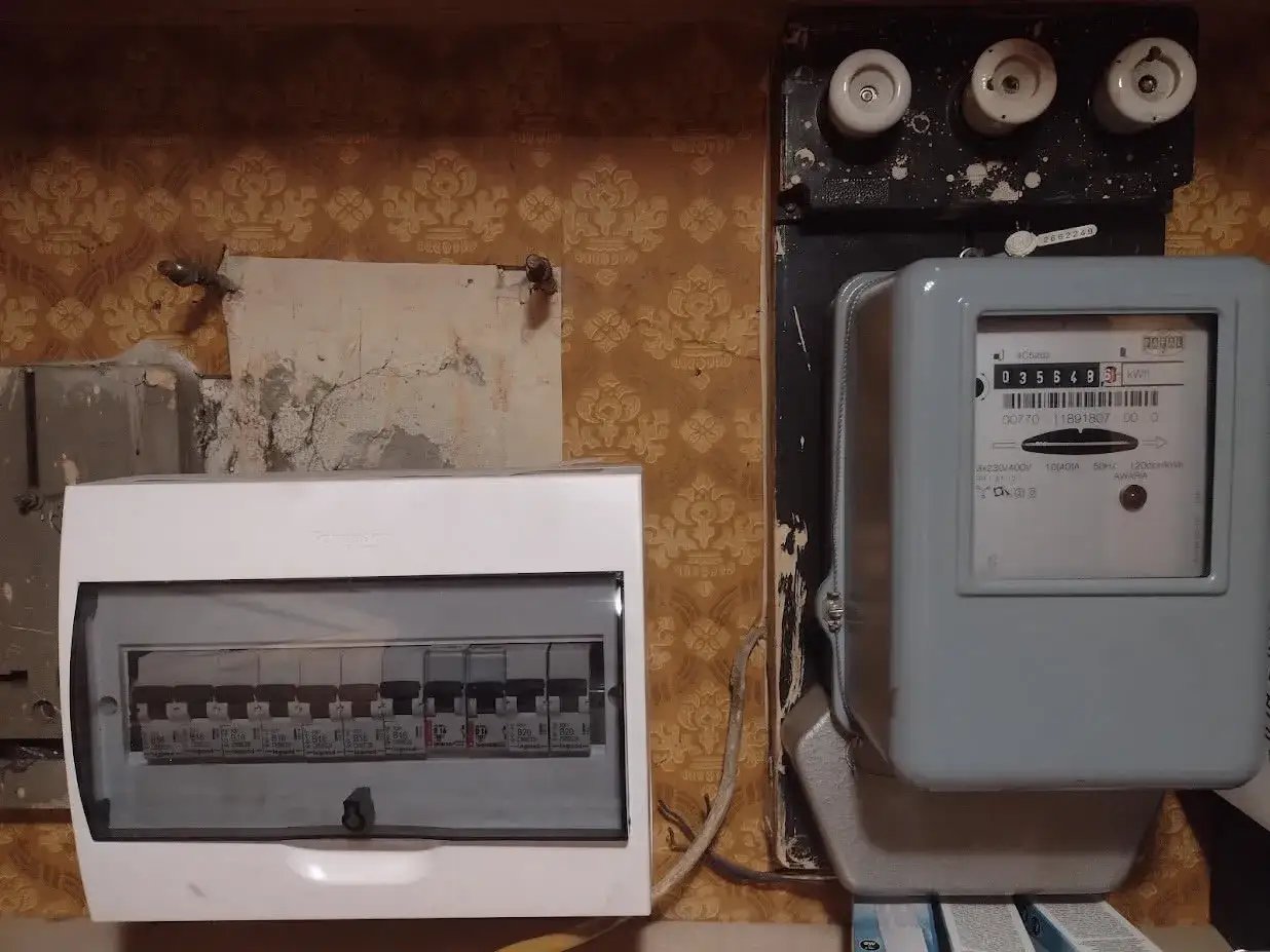 Nowa rozdzielnica elektryczna w domu jednorodzinnym obok starego licznika i bezpiecznik&oacute;w.