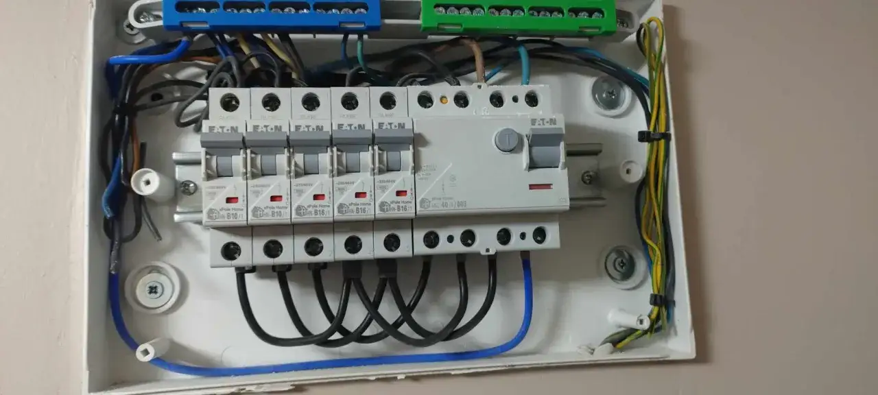 Nowoczesna instalacja elektryczna w trakcie prac. Widoczny rozdzielacz z bezpiecznikami i okablowaniem.