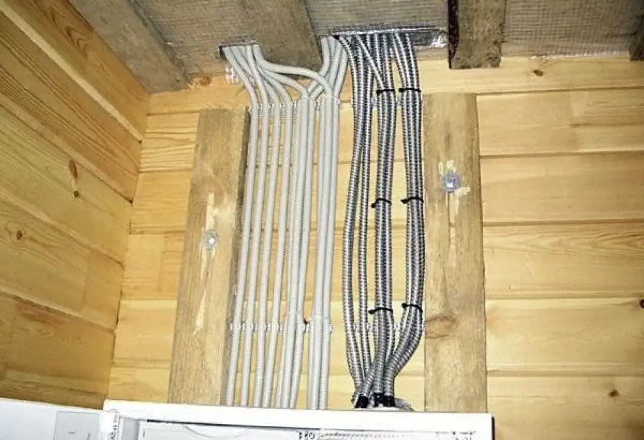 Instalacja natynkowa w rurkach, szare i metalowe peszle prowadzą do sufitu.