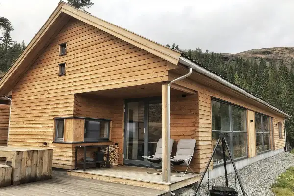 Nowoczesny dom norweski z drewnianą elewacją, tarasem i widokiem na las.
