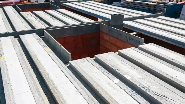 Budowa domu: betonowe belki stropowe czekają na montaż. To właśnie strop co to jest, decyduje o podziale pięter.