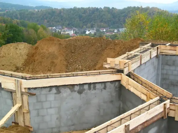 Fundamenty domu w budowie, zbrojenie i szalunki gotowe do zalania betonem. To pierwszy krok do pozwolenia na budowę.