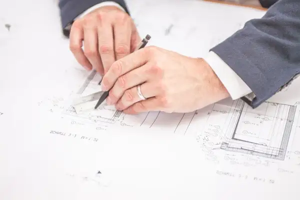 Rysowanie planów budowlanych. Czy można zmienić plan zagospodarowania przestrzennego? Inżynierowie analizują dokumentację techniczną.